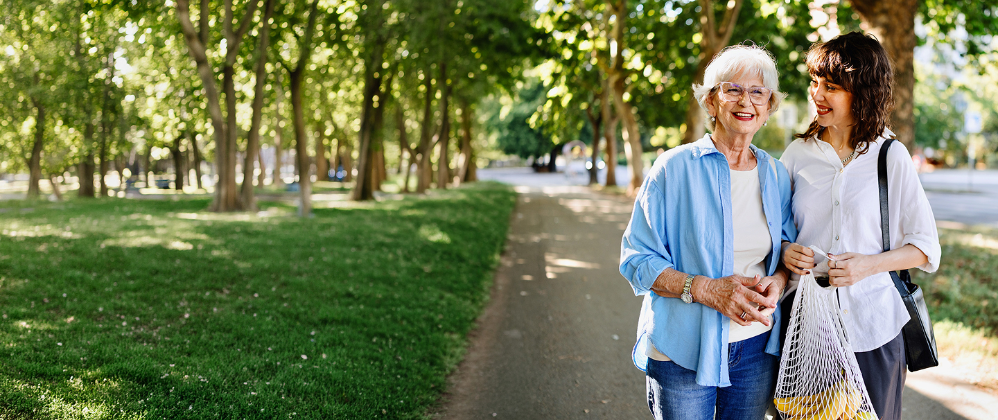 Older woman walking on sidewalk with younger woman